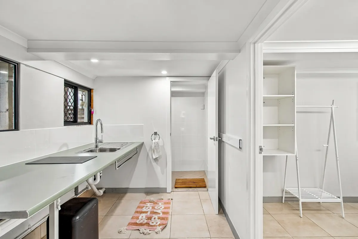 Granny flat kitchenette with sink and cooktop, bathroom beyond